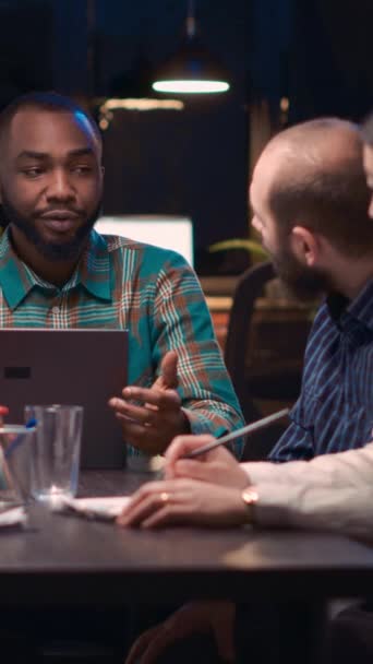 垂直视频 商务会议上在笔记本电脑屏幕上显示数据可视化的非洲裔美国分析专家 团队合作 不同的同事在夜间讨论公司报告 — 图库视频影像