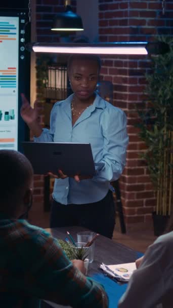 垂直视频 员工提供财务报告 显示图表在笔记本电脑屏幕上 非裔美国妇女统计介绍 讨论分析 规划销售战略的多样化小组 — 图库视频影像