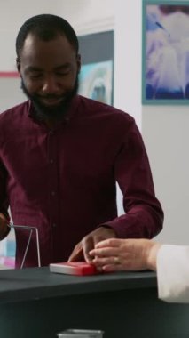 Dikey video: İlaç ürünlerini tezgaha koyup ilaç parasını ödemeye hazırlanan kişi kuyrukta bekliyor. Eczane masasından kutu kutu ilaç ve takviye alan bir genç..