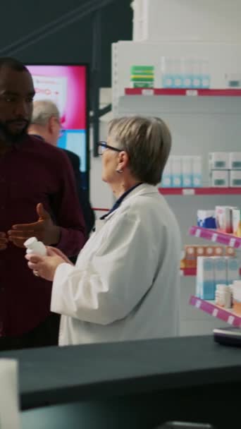 垂直录像 非洲裔美国人询问有关药丸治疗的专家 希望从药店购买药物和维生素 与老年妇女谈论医疗保健 — 图库视频影像