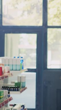 Dikey video: Reçeteli kağıdı olan bir erkek hasta tedavi hakkında uzman sorular soruyor, eczane raflarından ilaç ve vitamin satın almak istiyor. Eczanedeki malzeme kutularını işaretliyorum..