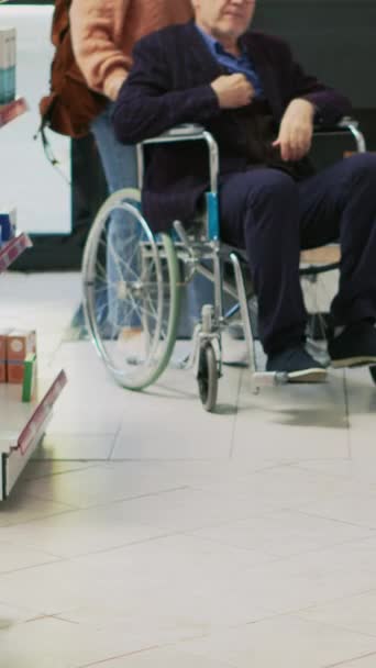 垂直ビデオ 薬局で治療を探している介護者と障害のある老人 薬についての専門家に話して 車椅子で身体障害者 介護者からのお願い — ストック動画