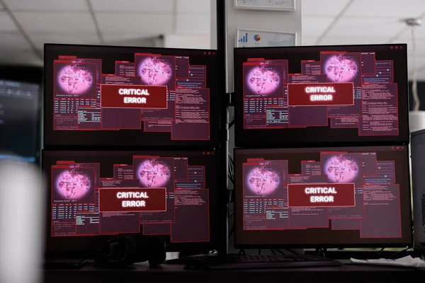 Computers displays having critical error message flashing on screen, showing hacking alert and security breach warning. Empty it company office with multiple monitors running cyber crime attack.