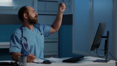 Hasta akciğerlerini analiz eden doktor hemşire hastane ofisinde saatlerce çalışırken bilgisayarda tıbbi uzmanlık yazıyor. Hastalığı tedavi etmek için ilaç tedavisi planlayan pratisyen asistanı