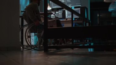 Terminal penceresinde kaynak kodunu yazma engelli genç programcı, birden fazla ekranda görüntülendi. IT kodlayıcı tekerlekli sandalye kullanıcısı gece geç saatlerde ofiste yeni kullanıcı arayüzü programlıyor. Üçayak atışı.
