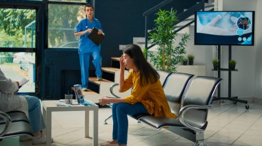 Kadın hemşire hastayı uzman doktorla görüşmeye götürüyor. Bekleme odasında oturuyor. Sağlık kontrolünde doktorla konuşmak için bekleyen Asyalı kadın..