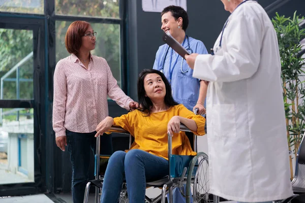 담당의 휠체어 사용자와 상담하고 지역에 부상당한 환자를 가병을 환자에게 조언을 — 스톡 사진