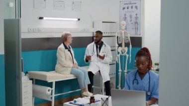 Diverse people doing medical consultation in clinical office, attending checkup visit appointment with facility staff. Doctor and patient talking about medicine and healthcare at examination.