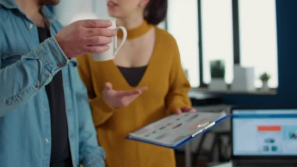 员工拿起一杯咖啡或茶 一边喝酒 一边和同事拿着写字板和图表聊天 临时男子与在职女同事讨论商业战略 — 图库视频影像