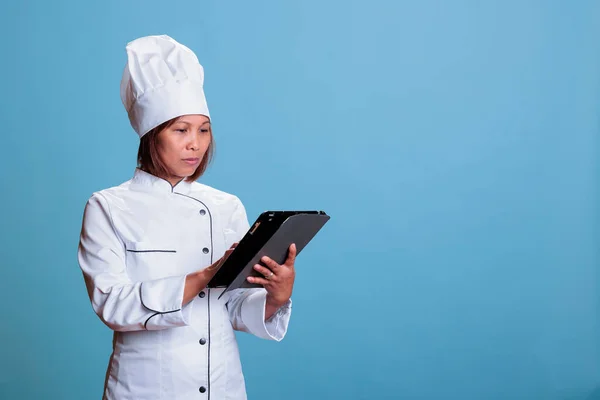 Önlüklü Beyaz Üniformalı Ciddi Bir Aşçı Elinde Tablet Bilgisayarla Gastronomi — Stok fotoğraf