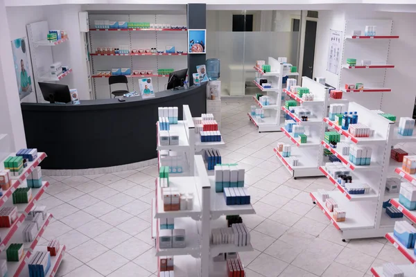 Empty pharmacy with nobody in it having shelves full with pharmaceutical products ready for opening. Drugstore desk full with clients medical prescription. Health care products, medicine service