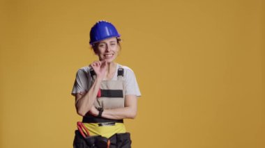 İnşaat işçisinin sessiz tabelası, reklam sessizliği ve gizlilik hareketi yapan portresi. Stüdyonun arka planında sır saklayan ve gizli bir sembol gösteren kadın inşaatçı..