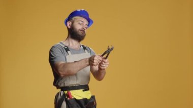 İnşaat işçisi yenileme projesinde çelikle çalışıyor. İnşaat ve onarım için paslanmaz anahtar kullanıyor. Erkek müteahhit yenileme işi için kıskacı çeviriyor.