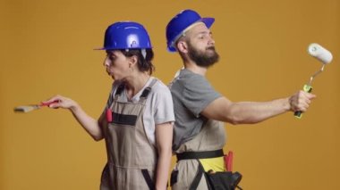 Boya fırçası ve silindirle duvarları boyama becerisine sahip bir inşaat ekibi, fırça ve renkleri yenilemek için kullanıyor. İnşaatçılar stüdyoda yeniden geliştirme ve inşa üzerinde çalışıyorlar..