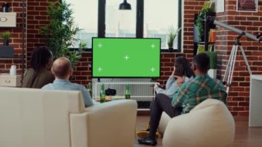 Çeşitli insanlar yeşil ekran şablonunda televizyon kanallarını değiştiriyor, televizyon programını izliyor ve izole edilmiş kroma anahtar arka planına bakıyor. Boş kopyalama alanı kullanılıyor. Üçayak atışı.