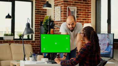 Masaüstü bilgisayarında boş kroma anahtar şablonu kullanarak yeşil ekranlı bilgisayarı analiz eden çeşitli çalışanlardan oluşan bir ekip. Arka planda izole edilmiş bir kopyalama alanı görüntüsüyle çalışan kadın ve erkek.