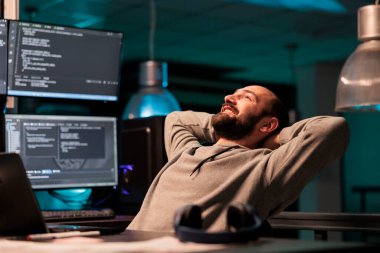 Mutlu gevşemiş geliştirici koltuğuna yaslanmış, ofisteki yazılım geliştirme çalışmalarından memnun. Sunucu programlama başarısı, sunucu kodu html betiği.