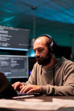 Genç uygulama geliştiricisi kod yazıyor ve kulaklıkla müzik dinliyor, büyük verileri programlamak için yapay zeka senaryosu kullanıyor. Terminal penceresinde sunucu programlanıyor.