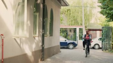 Bisikletli Afrika kökenli Amerikan kuryesi insanlara paket servis yapan bir kurye olarak çalışıyor. Bisiklete binen ve paket paket restoran yemekleri getiren bir kadın..