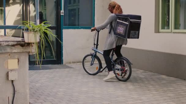 速递食品服务快递员将午餐装在纸袋中运送 并在前门下速递食品订单 微笑的客人在外面吃饭 骑自行车的女人带着包裹 — 图库视频影像