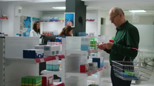 シニアのお客様は 処方薬や医薬品を購入する準備をしながら 薬局の循環器系薬箱を笑って見ています 棚のサプリメントや薬のチェック — ストック動画