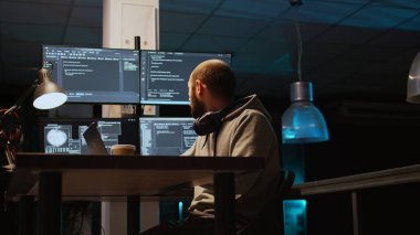 Sistem programcısı, güvenlik duvarı sunucusu oluşturmak için programlama dilini kullanarak dizüstü bilgisayarda ve birden fazla monitörde kaynak kodu yazıyor. Kodlayıcı veritabanı bulut hesaplaması geliştiriyor. El kamerasıyla..