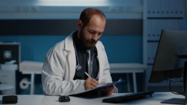 Genel pratisyen hekim, bilgisayar raporlarını kağıt üzerine yazılmış uzmanlıkla karşılaştırıyor ve hastane ofisinde saatlerce hasta teşhisi üzerinde çalışıyor. Sıhhiye planlama sağlık tedavisi