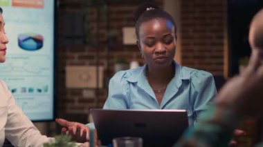 Stratejik Planlama İş Toplantısı, Afrikalı Amerikalı bir çalışan sunumu yakından açıklıyor. İş arkadaşları beyin fırtınası, strateji tartışması, şirket araştırma analizi raporu