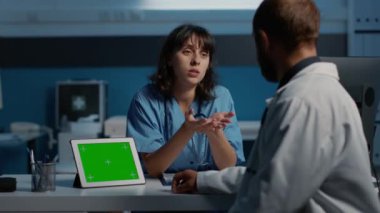 Muayene sırasında tablet bilgisayarı yeşil ekran ekranlı analiz edilirken doktorla tıbbi raporu tartışmamak. Klinik personeli gece geç saatlere kadar hastane ofisinde çalışıyor. Sağlık hizmetleri