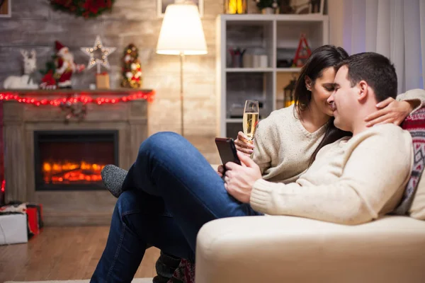 Joven Sosteniendo Teléfono Inteligente Mientras Muestra Afecto Esposa Día Navidad —  Fotos de Stock