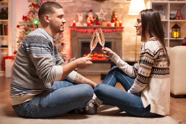 在圣诞节那天 一对浪漫的夫妇在温暖的壁炉前 碰着一杯香槟酒 — 图库照片
