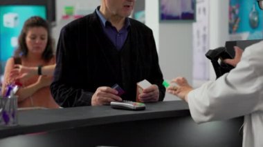 Yaşlı bir adam uyuşturucu kutularına kredi kartıyla ödeme yapıyor. Reçeteli tedavi için bağlantısız ödeme yapıyor. Eczane tezgahına tıbbi ürünler koymak, kasada ödeme yapmak. El kamerasıyla..