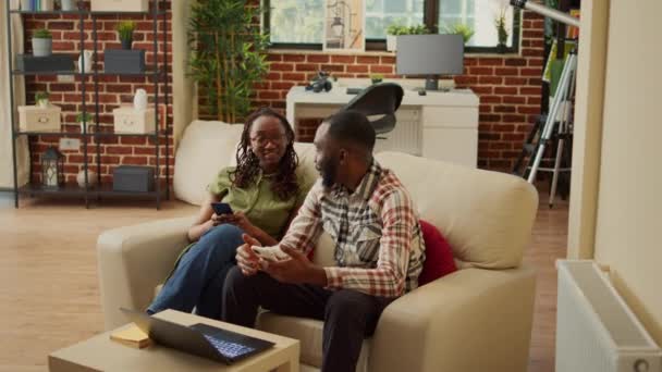 恋爱中的年轻伴侣舒适地坐在家里 在手机上浏览社交媒体应用程序 放松身心 男朋友和女朋友用智能手机舒服地睡在沙发上 — 图库视频影像