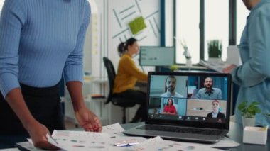 Afrikalı Amerikalı bir kadın müşteriler ve yöneticilerle çevrimiçi toplantıda dizüstü bilgisayar kullanarak pazarlama stratejisi hakkında konuşuyor. Video konferansında çalışan bir iş adamı satışları tartışıyor.