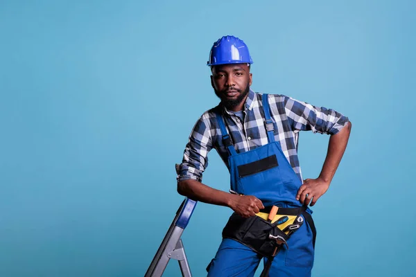 Serious Builder Leaning Ladder Wearing Coveralls Protective Helmet Looking Camera — Stock Photo, Image