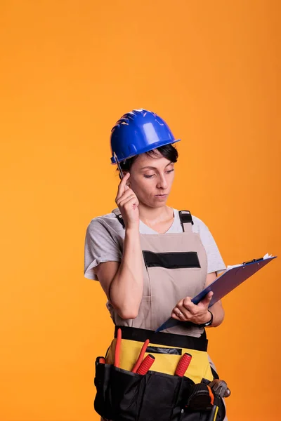 女承包商在工作室里用剪贴板文件集思广益 在文件上做笔记 并考虑更新解决方案 工业工程师利用测量结果建造工地 — 图库照片