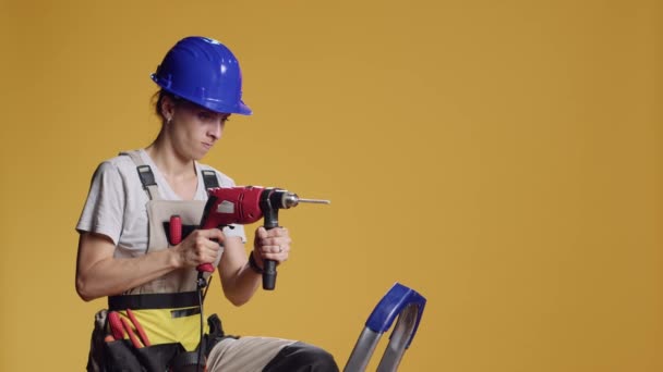 여자가 총으로 스튜디오에서 작업복을 기계로 건축하고 건축하는 수리하는 — 비디오
