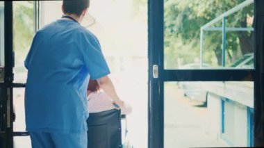 Tekerlekli sandalyedeki kadın kullanıcıyı randevuya götüren tıbbi asistan, tesisteki kronik bozuklukla ilgileniyor. Hemşire fiziksel engelli Asyalı kadına yardım ediyor, sağlık hizmetleri rehabilitasyonu.