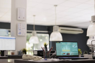 Modern ofisteki endüstriyel lambalı finansal yazılımın olduğu masa üstünde. Finansal ve yatırım uzmanlarından oluşan şirkette boş iş istasyonları, iç işyeri kavramı.