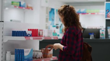 Eczanedeki ilaç ve vitaminlerle rafları inceleyen kadın müşteri, ilaç almak için ilave paketlere bakıyor. İlaç ürünlerini ve ilaç şişelerini kontrol ediyorum..