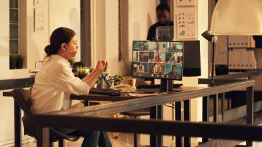 Gün batımında iş videosu toplantısına katılan bir kadın çevrimiçi video konferansında iş arkadaşlarıyla konuşuyor. Uzaktan telekonferans bağlantısı üzerinden sohbet, yönetici sohbeti.