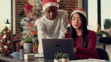 Kış tatilinde, başlangıç işinde fikir üreten, bilgisayar üzerinde takım çalışması yapan ve Noel Baba şapkası takan çeşitli kadınlar. Yılbaşı kutlamalarından önce ofiste çalışmak.