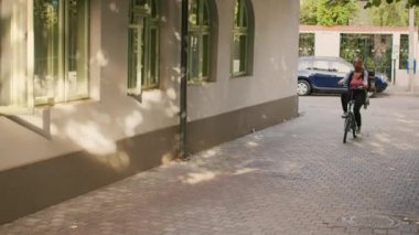 Bisikletli Afrikalı Amerikalı kadın restoran siparişlerini teslim etmek için müşteri ön kapısına gidiyor. Bisiklete binen ve müşterilerine fast food veren genç bir taşıyıcı..