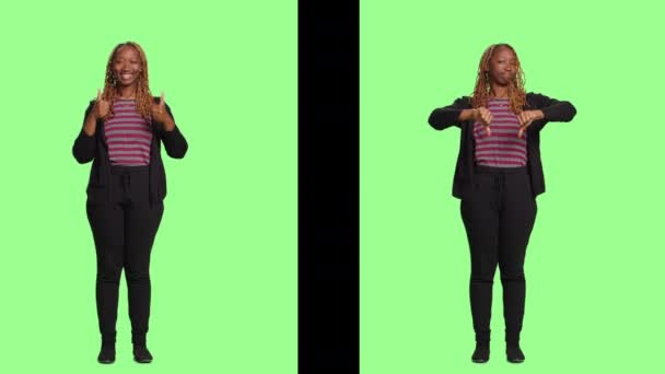 在绿屏背景的两边 女人的大姆指向上 大姆指向下 做喜欢和不喜欢的动作 全身都站在背后 好的和坏的负面符号 — 图库视频影像