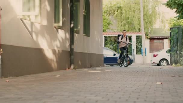 作为送餐快递员 妇女骑着自行车在街上工作 背着热背包在前门送餐 女性承运人向客户发出快餐订单 手持射击 — 图库视频影像