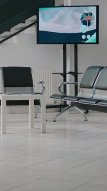 Dikey video: Bekleme odası sandalyeli boş hastane resepsiyon alanı, klinikte resepsiyon masası olan bekleme alanı. Check-up randevularına katılmadan önce beklemek için tıbbi tesis lobisi.