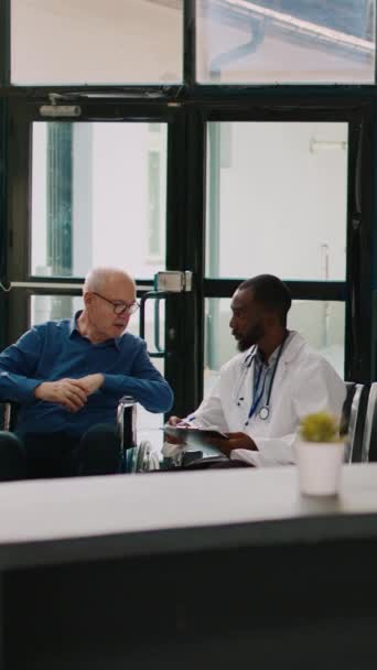 Vertikální Video Mladý Lékař Rozmlouvá Starším Mužem Recepci Provádí Lékařskou — Stock video