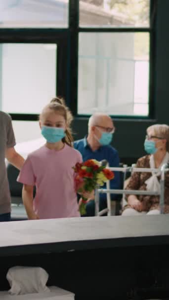Dikey Video Yüzü Maskeli Anne Çocuk Hastane Resepsiyonunda Resepsiyonistle Konuşuyor — Stok video