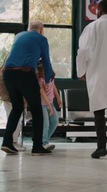 Dikey video: Endişeli büyükanneler ve büyükbabalar başları dönen çocukla birlikte konsültasyona gelip sağlık görevlilerinden acil durum muayenesi istiyorlar. Hasta küçük kız kendini hasta hissediyor. Bekleme odasında..