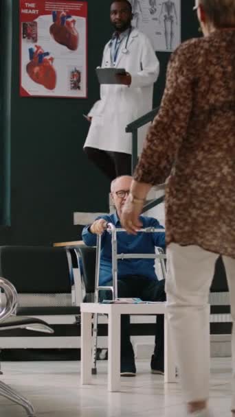Vertical Video Elderly Man Walking Frame Sitting Waiting Room Talking — Stock Video
